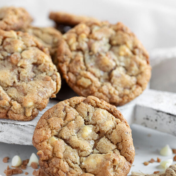 Toffee, walnut and white chocolate cookies on serving board.