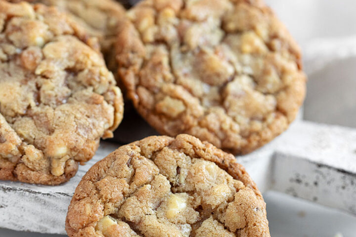 Toffee, walnut and white chocolate cookies on serving board.