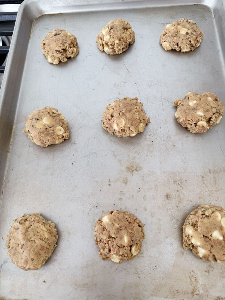 Cookie dough balls on the cookie sheet after flattening.