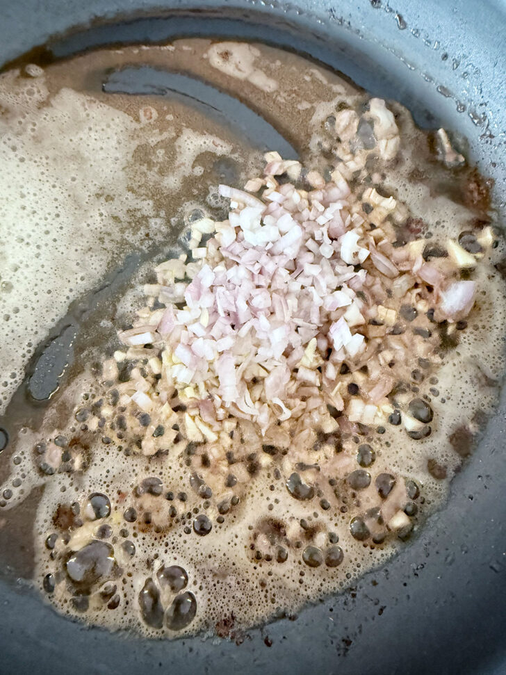Shallots cooking in butter in a skillet.