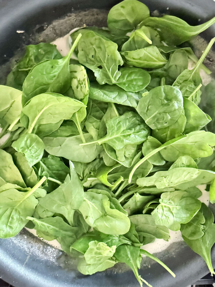 Adding fresh spinach to the sauce.