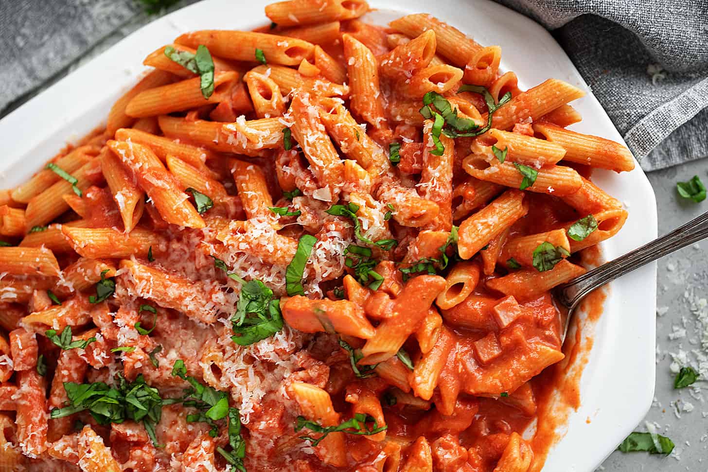 Ham and tomato sauce pasta on a large plate.