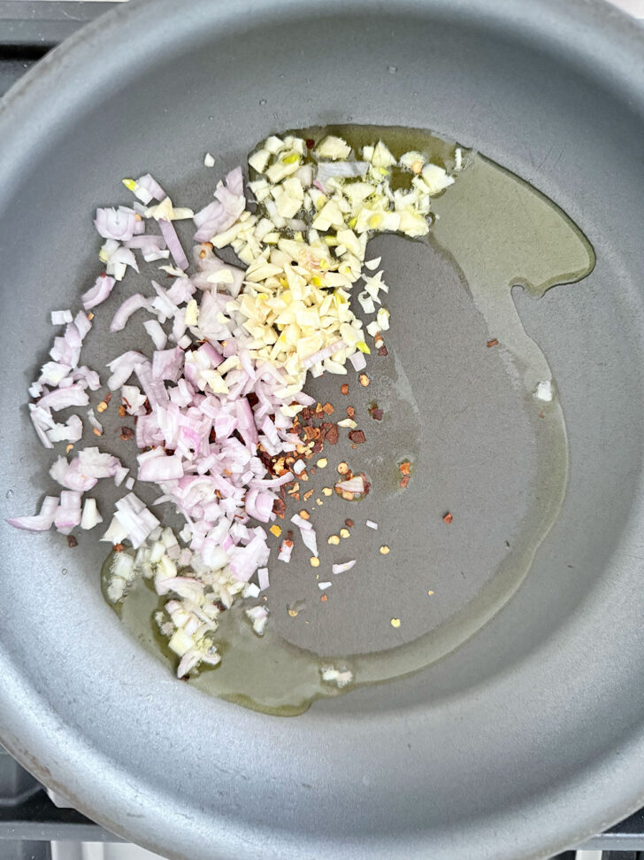 Garlic and shallots cooking in oil in a skillet.