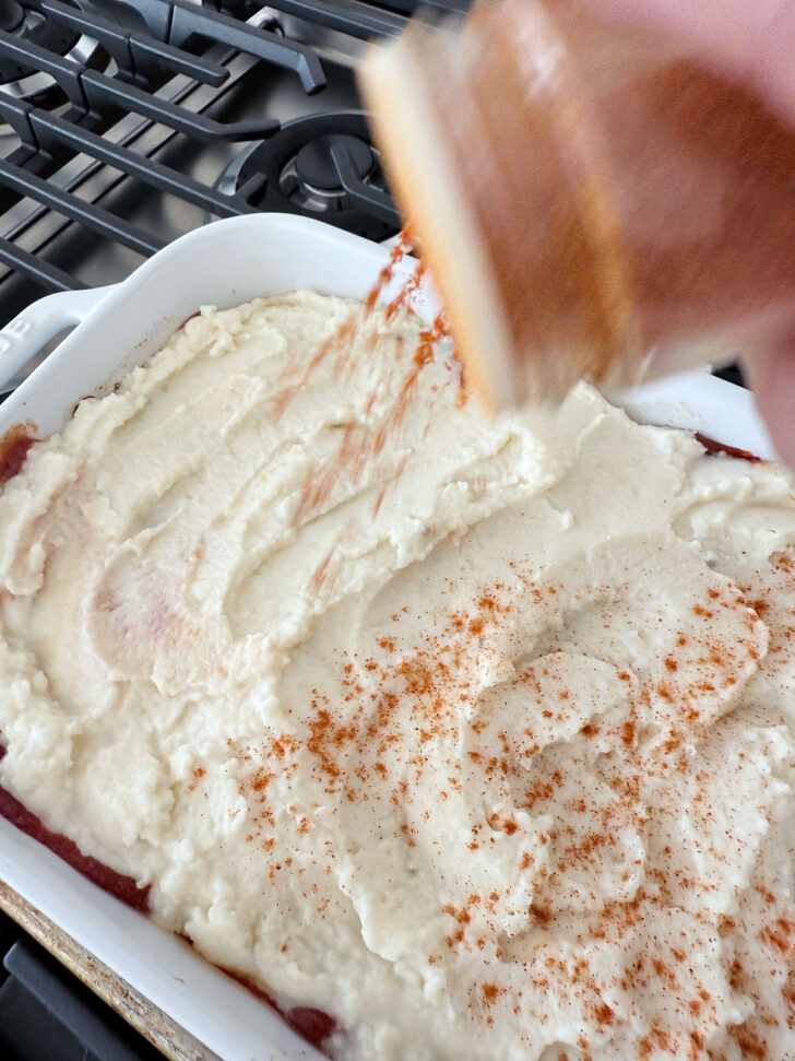 Sprinkling the mashed potatoes with paprika.