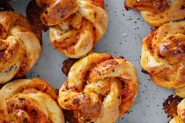 Pizza twists on a baking sheet.