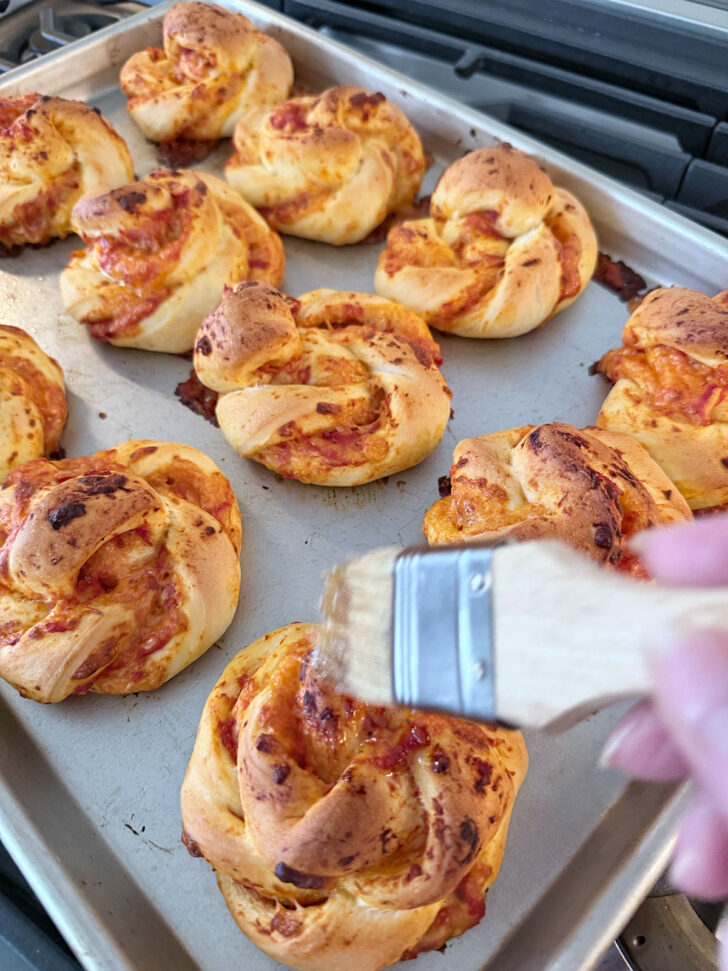 Finished pizza twists being brushed with garlic butter.