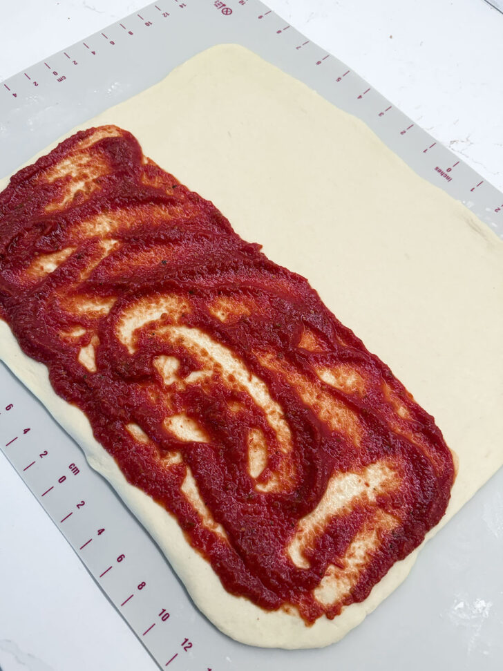 Pizza sauce spread onto half of the rolled out dough.