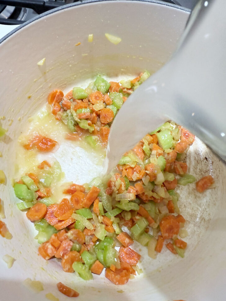 Adding broth to the cooked vegetables