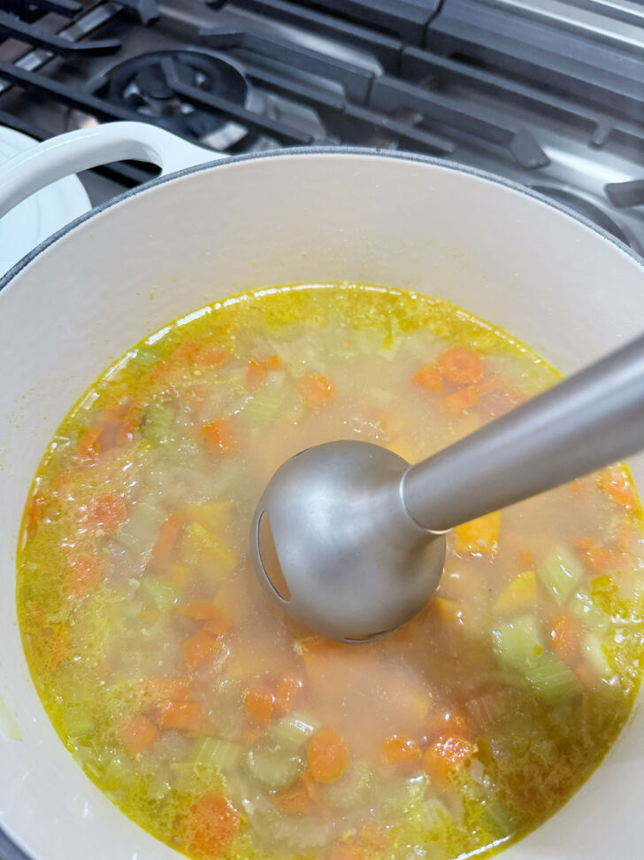 Using and immersion blender to puree the soup.