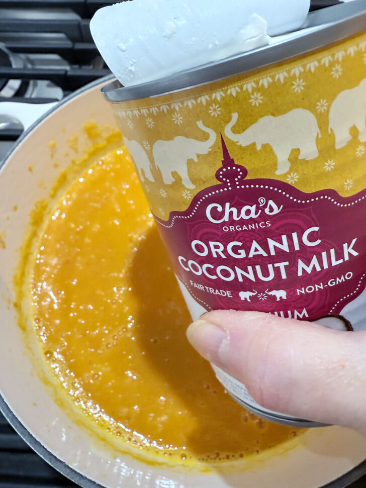 Adding coconut milk to the soup pot.