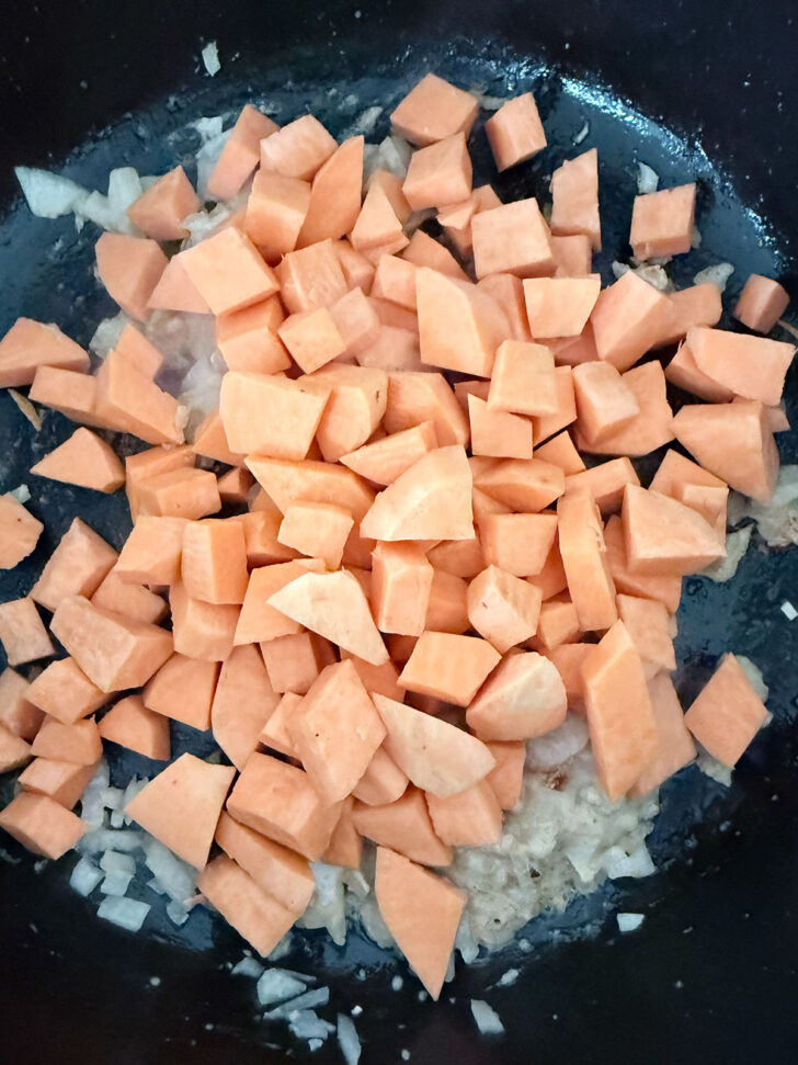 Adding the diced sweet potato to the skillet.