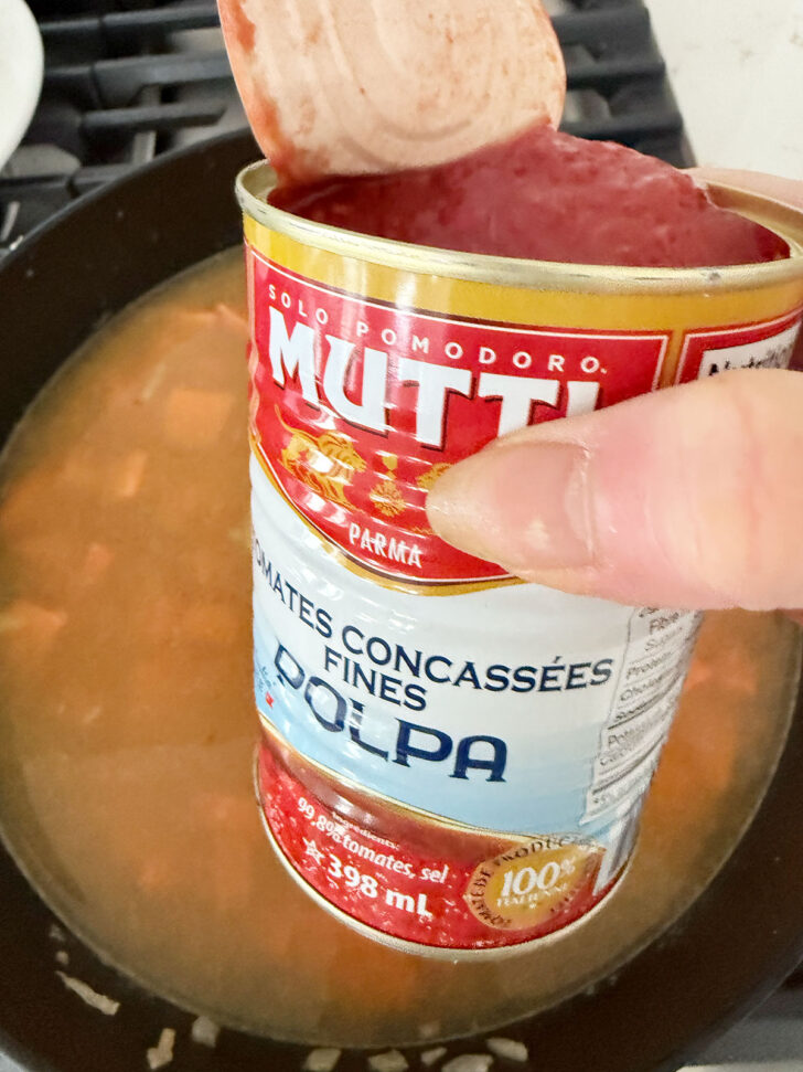 Adding the chopped tomatoes to the skillet.