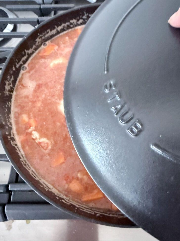 Placing a lid on top of the skillet.