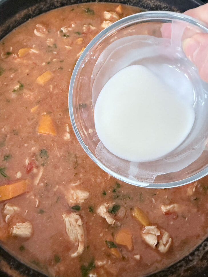 Thickening the African chicken stew with a cornstarch slurry.