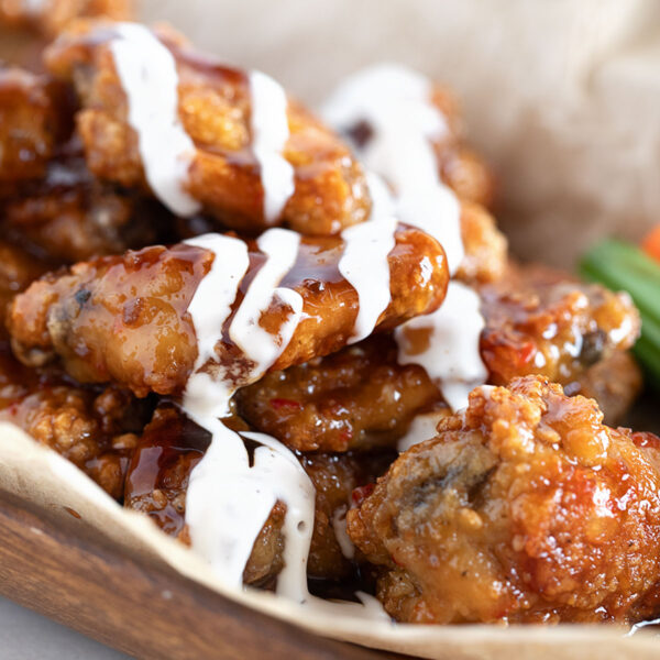 All-dressed saucy chicken wings on a serving board.