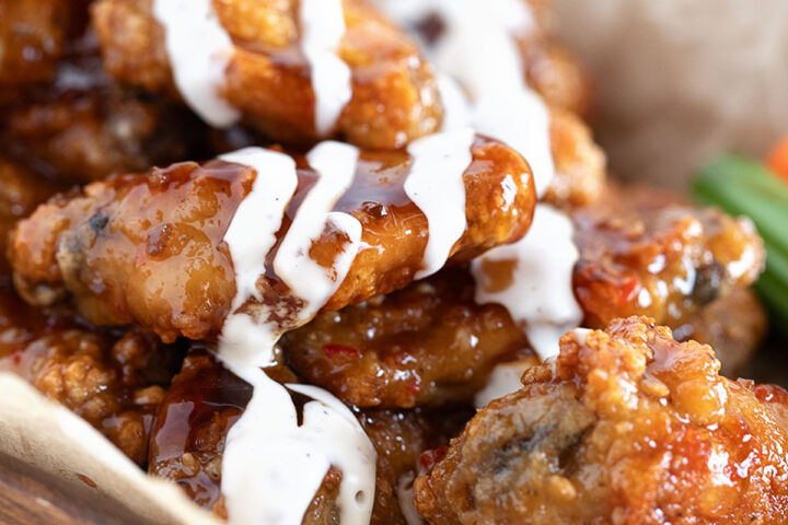 All-dressed saucy chicken wings on a serving board.
