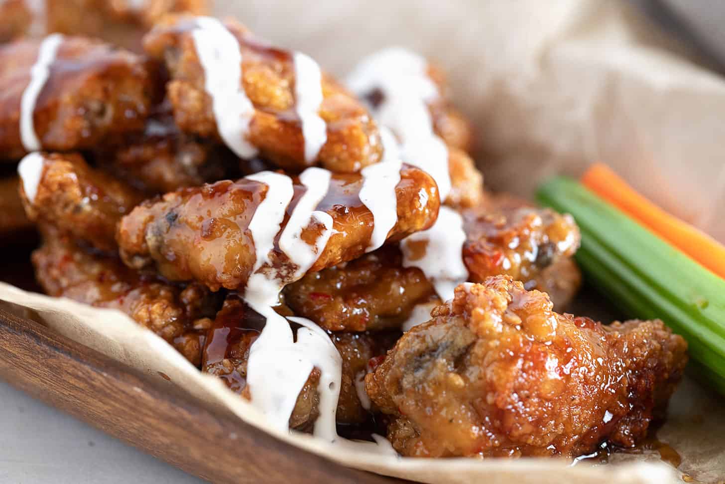 All-dressed saucy chicken wings on a serving board.