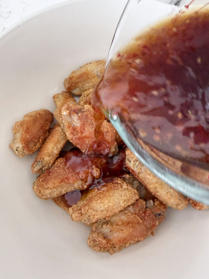 Adding sauce to the cooked chicken wings.