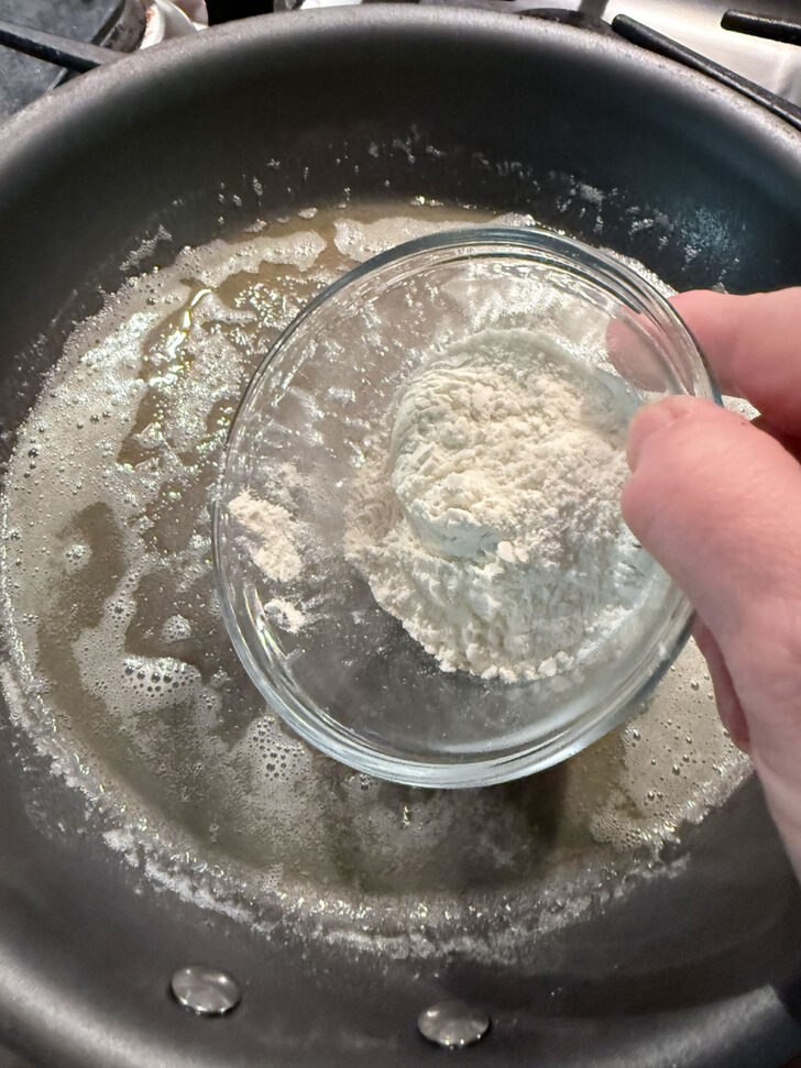 Adding flour to melted butter in a skillet.