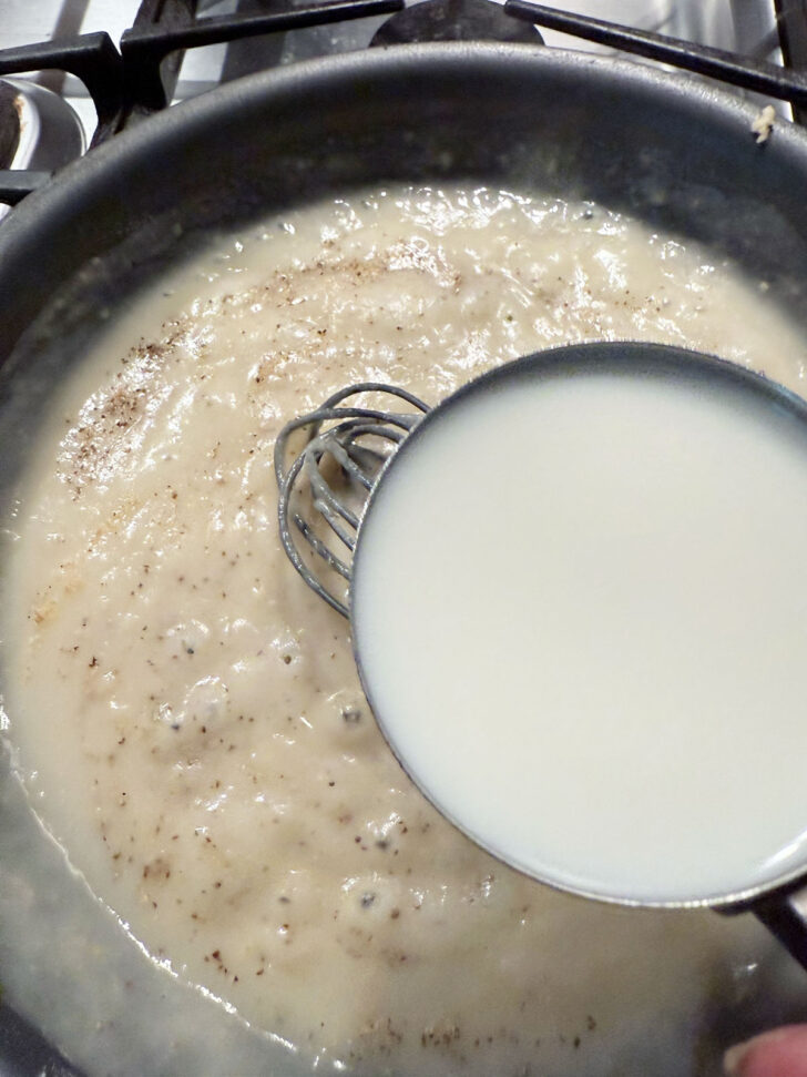 Adding milk to the skillet.