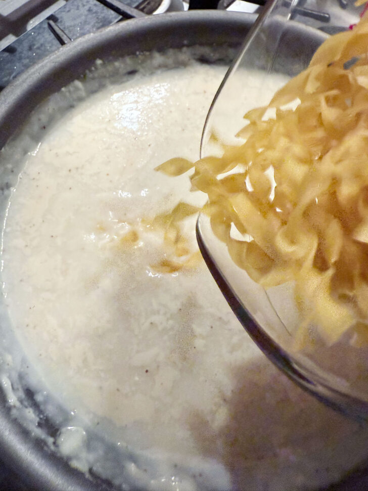 Adding egg noodles to the skillet.