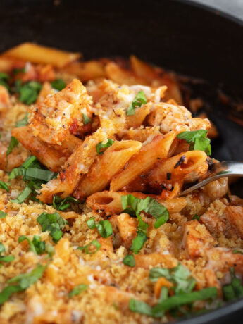 Chicken parmesan pasta in a skillet with a spoon.