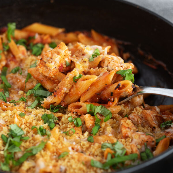 Chicken parmesan pasta in a skillet with a spoon.