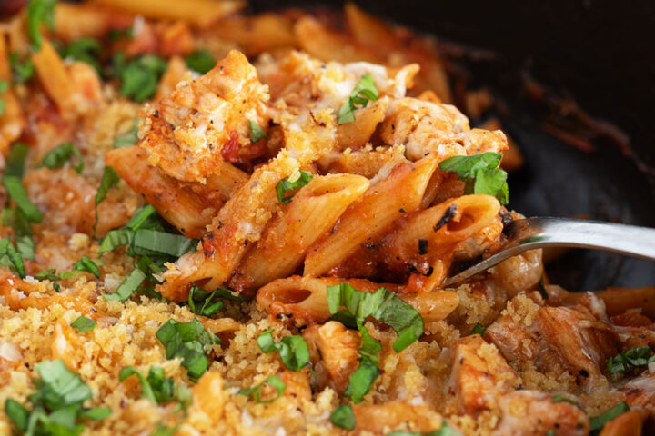 Chicken parmesan pasta in a skillet with a spoon.
