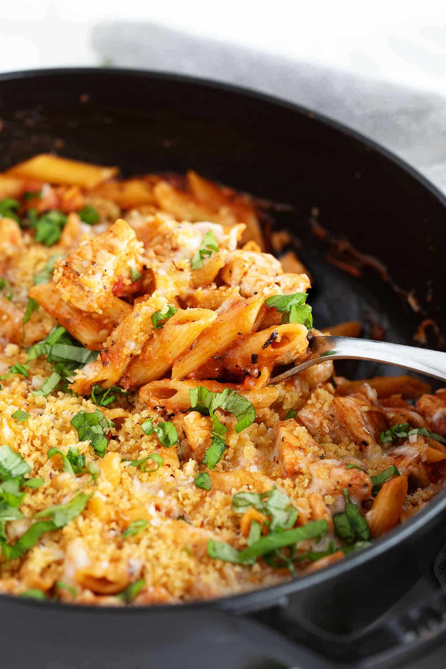 Chicken Parmesan pasta in the skillet with a spoon.