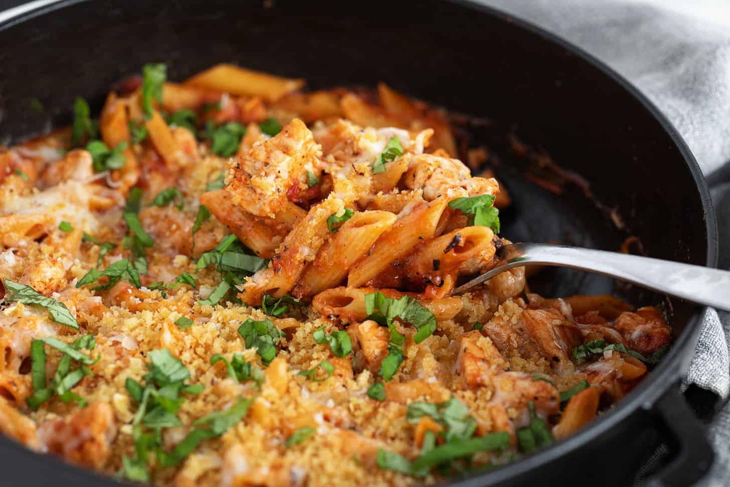 Chicken parmesan pasta in a skillet with a spoon.