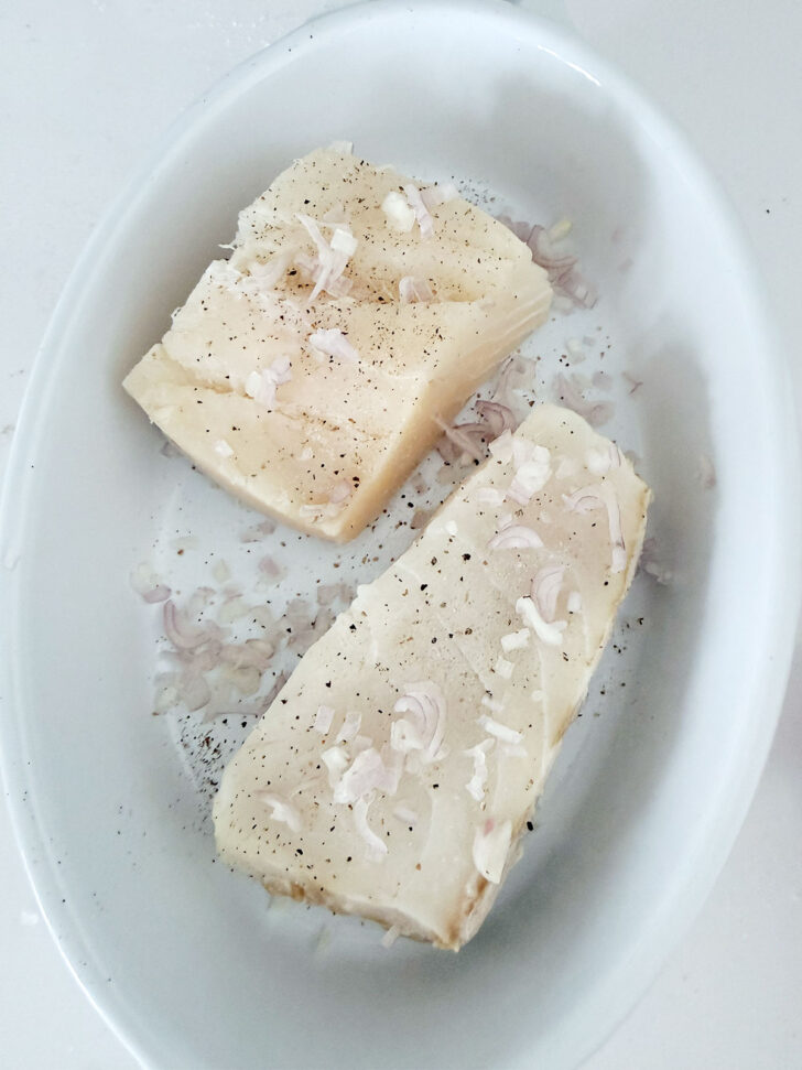 Shallots scattered over the halibut fillets.