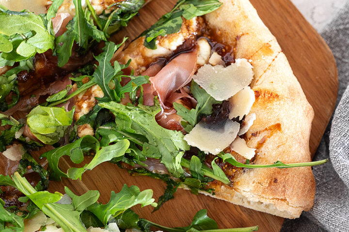 Fig and pig pizza sliced on a pizza peel.