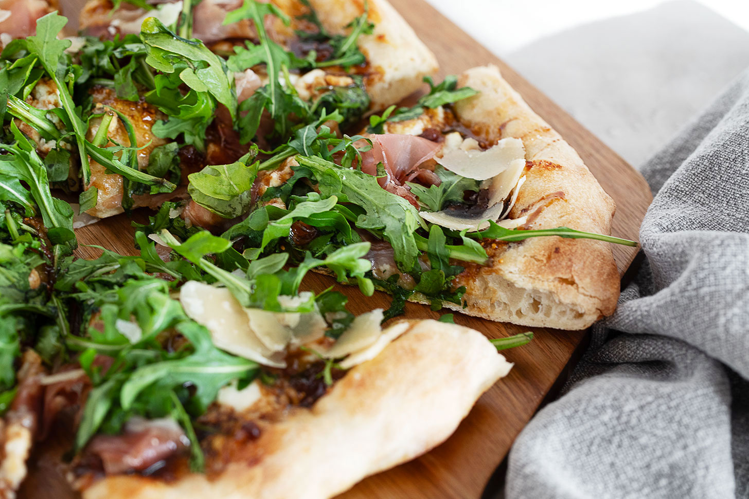 Fig and pig pizza on a pizza peel sliced.