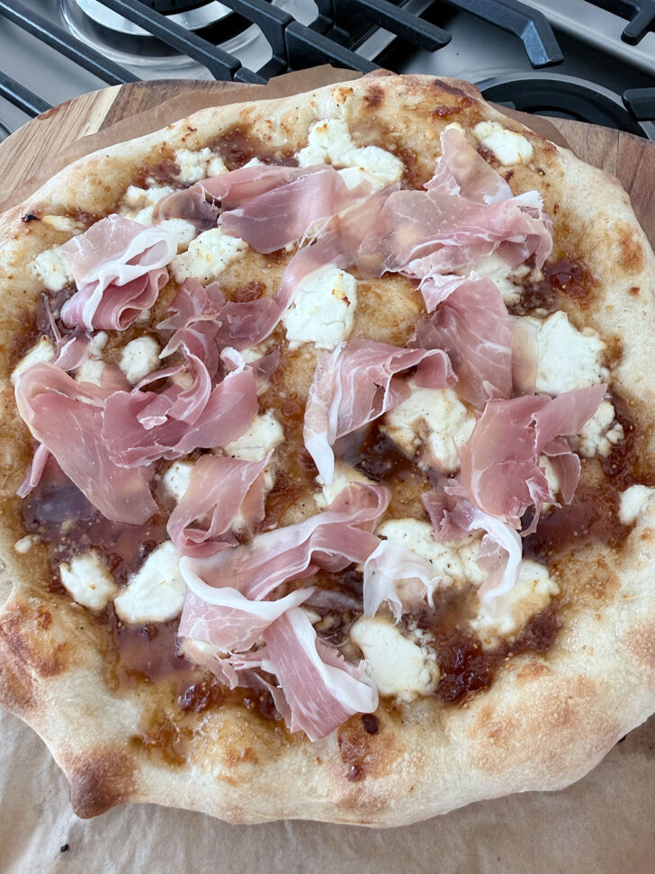 Prosciutto added to the baked pizza.