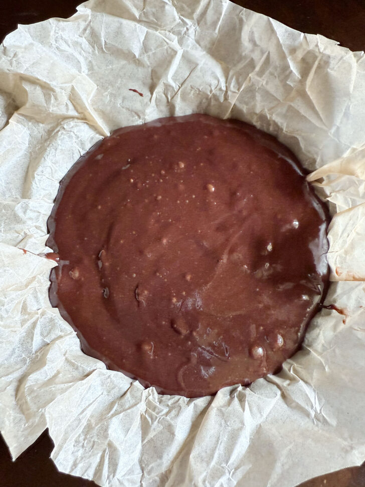 Brownie batter in a parchment-lined dish.