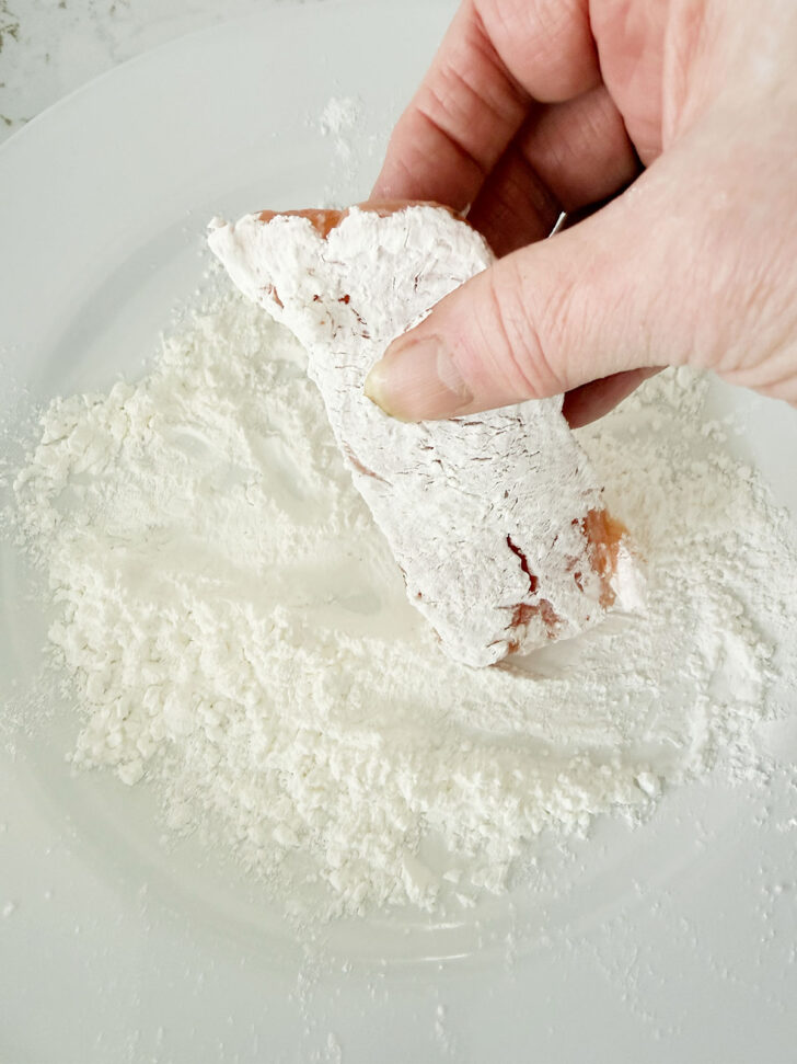 Dredging the salmon pieces in cornstarch.