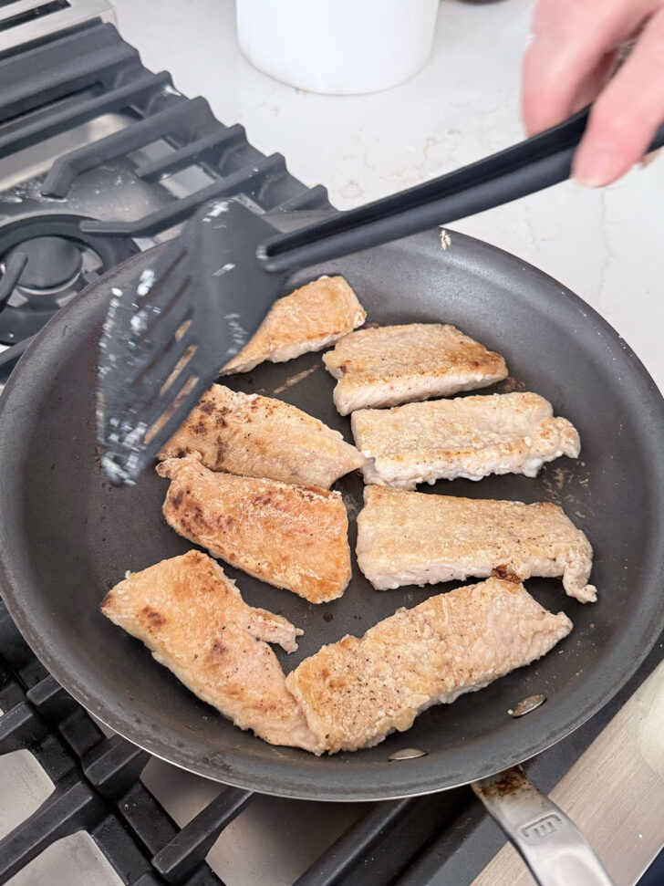 Pan frying the salmon until golden and crispy.