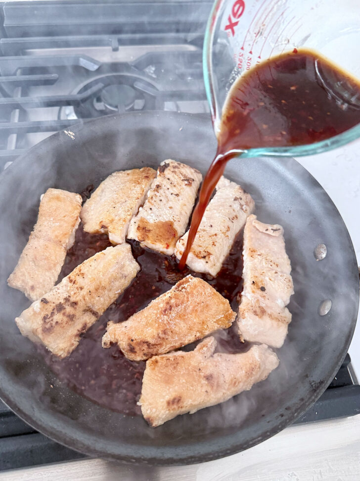 Adding the sauce to the crispy salmon.