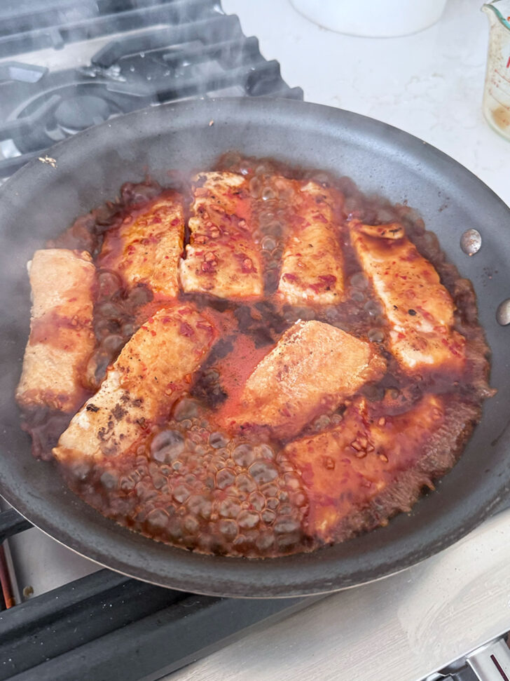 Sauce simmering with the salmon to thicken.