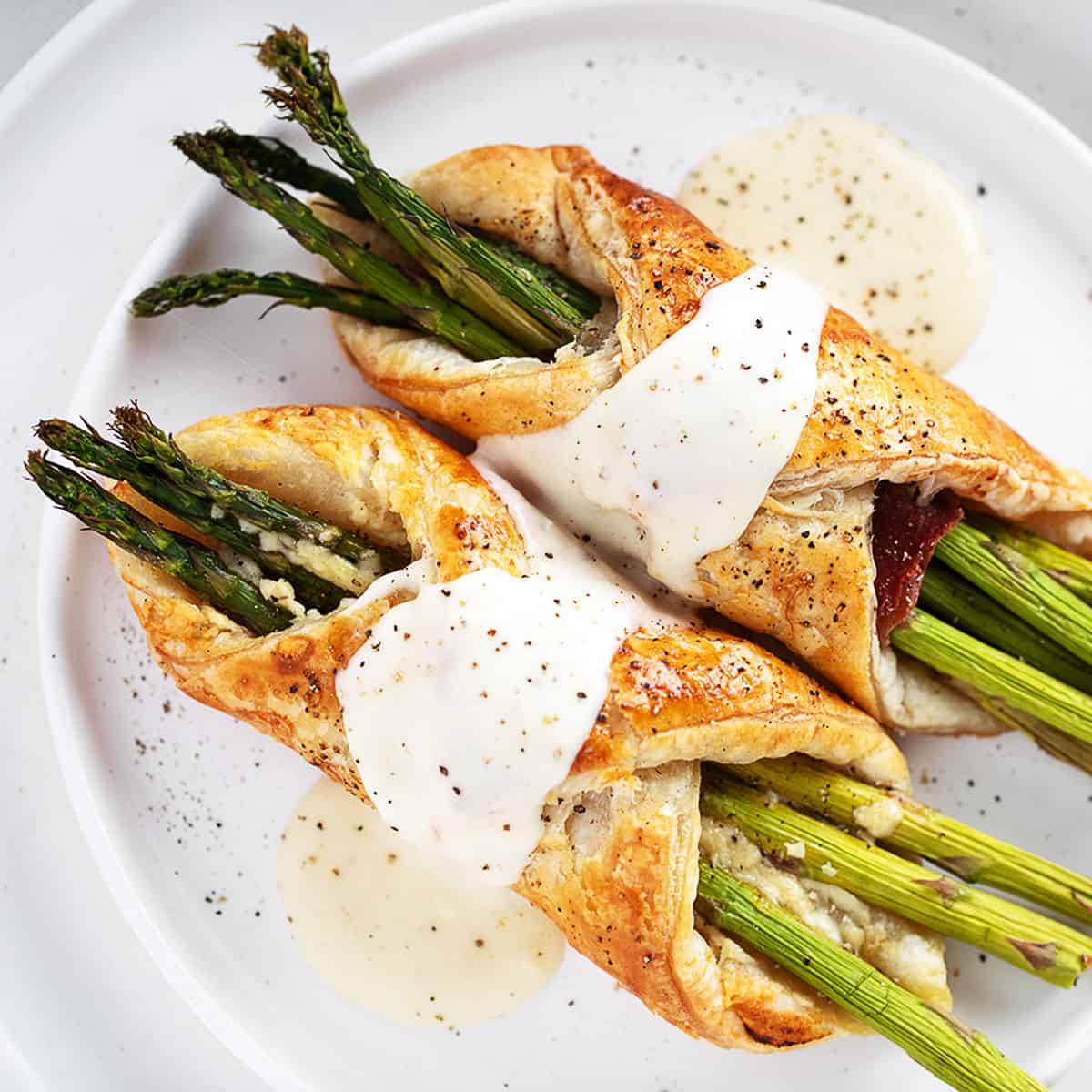 Asparagus filled puff pastry and prosciutto with cheese sauce.