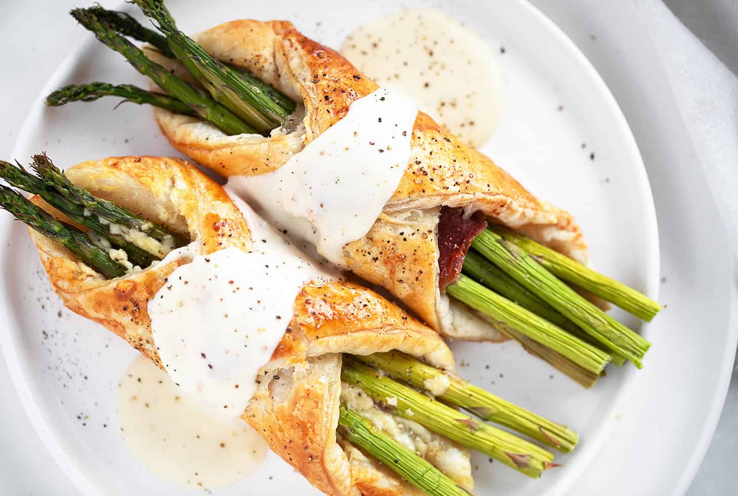 Asparagus filled puff pastry and prosciutto with cheese sauce.