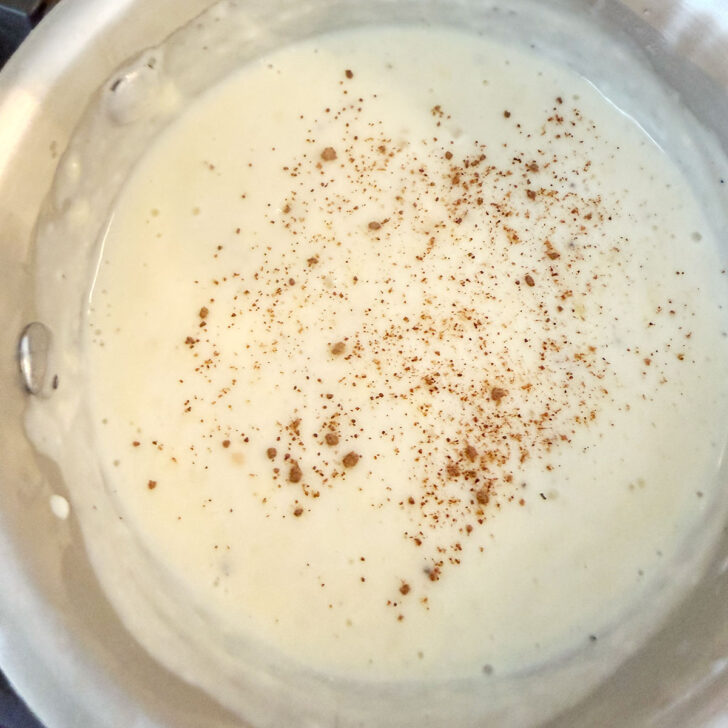 Adding nutmeg to the cheese sauce.