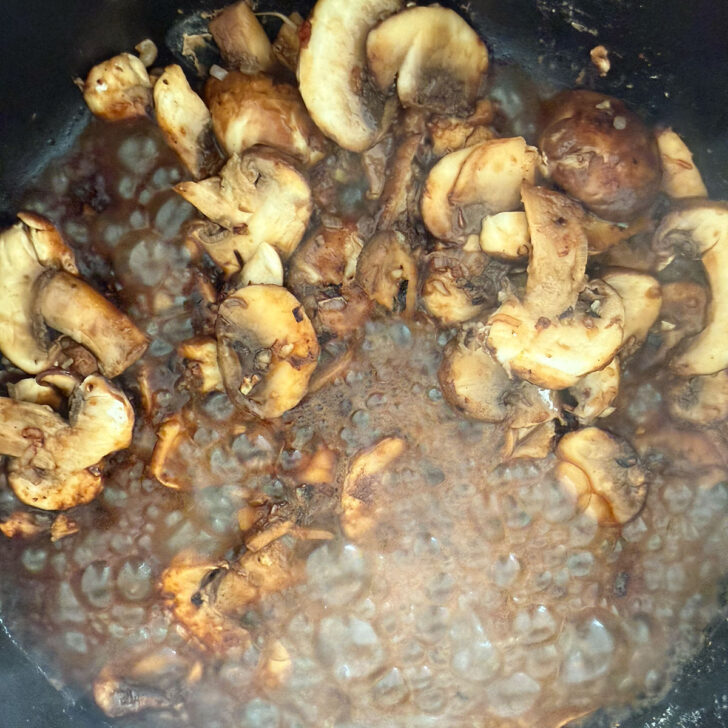 Marsala wine added to the mushrooms in a skillet.