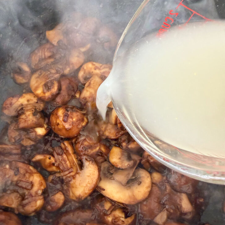 Adding the chicken broth to the pan.