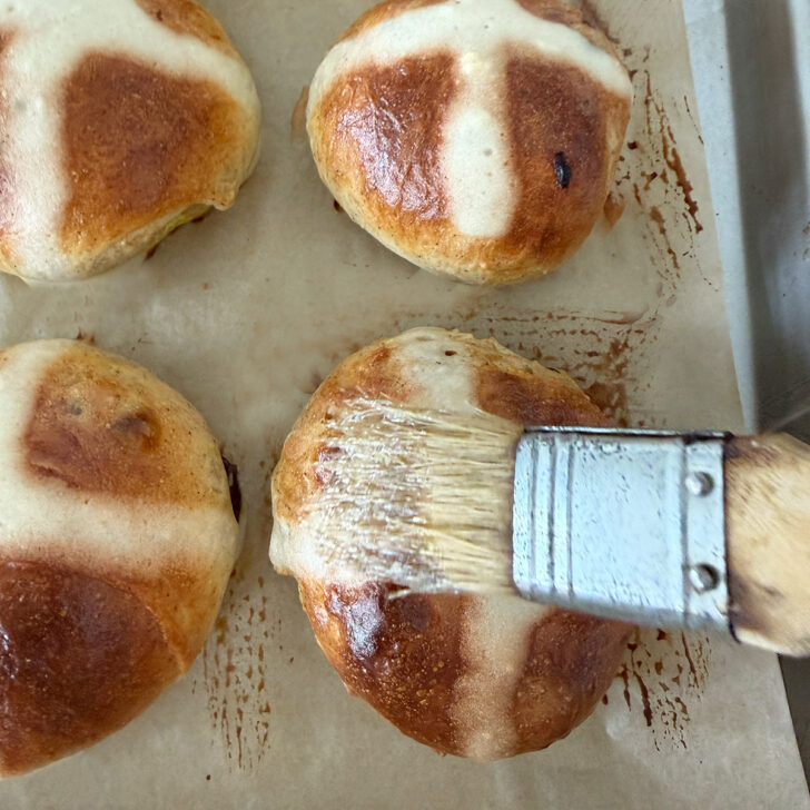 Brushing the sugar syrup onto the baked Earl Grey hot cross buns.
