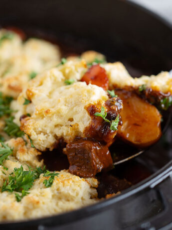 Guinness beef stew with a biscuit topping being spooned out.
