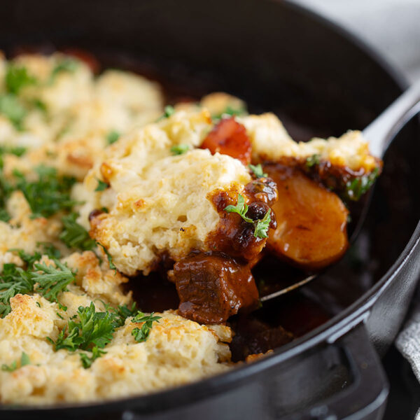 Guinness beef stew with a biscuit topping being spooned out.