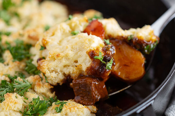 Guinness beef stew with a biscuit topping being spooned out.