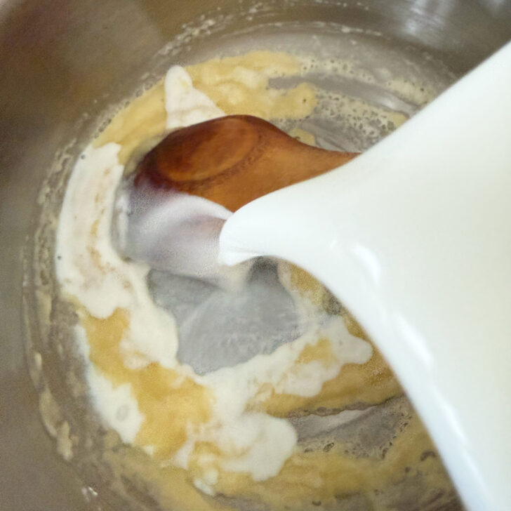 Adding milk to the butter and flour in the saucepan.