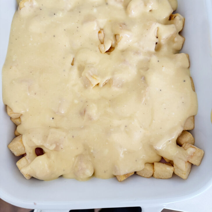 Adding some of the cheese sauce over the ham and hash browns in the casserole